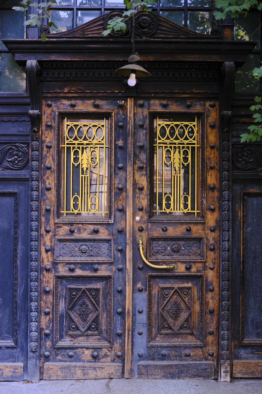 Weathered wooden double doors with yellow ornamental iron grilles and carved lower panels.