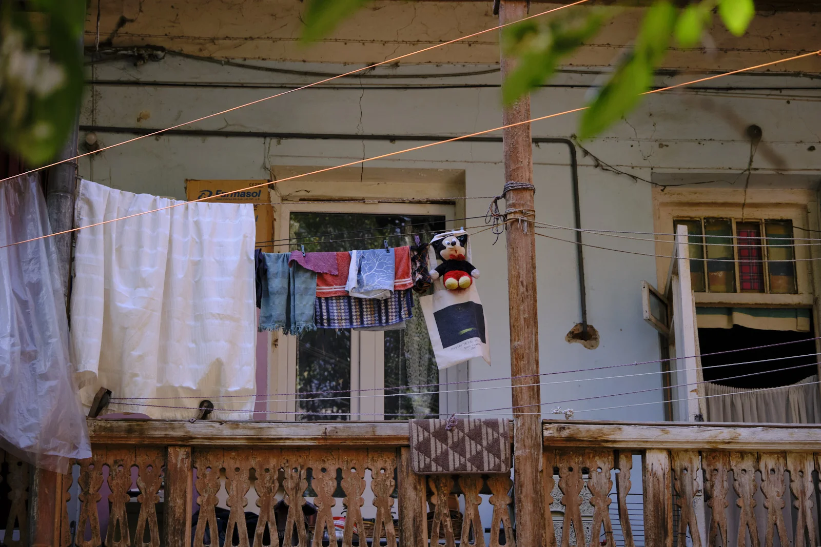 Laundry and a Mickey Mouse doll hanging on lines in front of a pale blue wooden house.