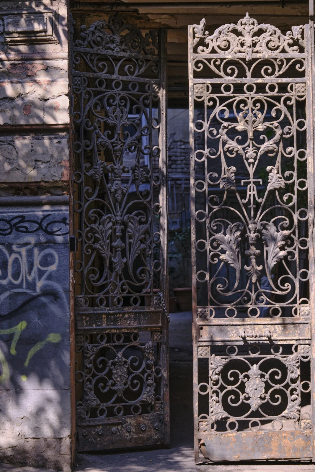 An iron gate with both leaves open in a brick doorway.