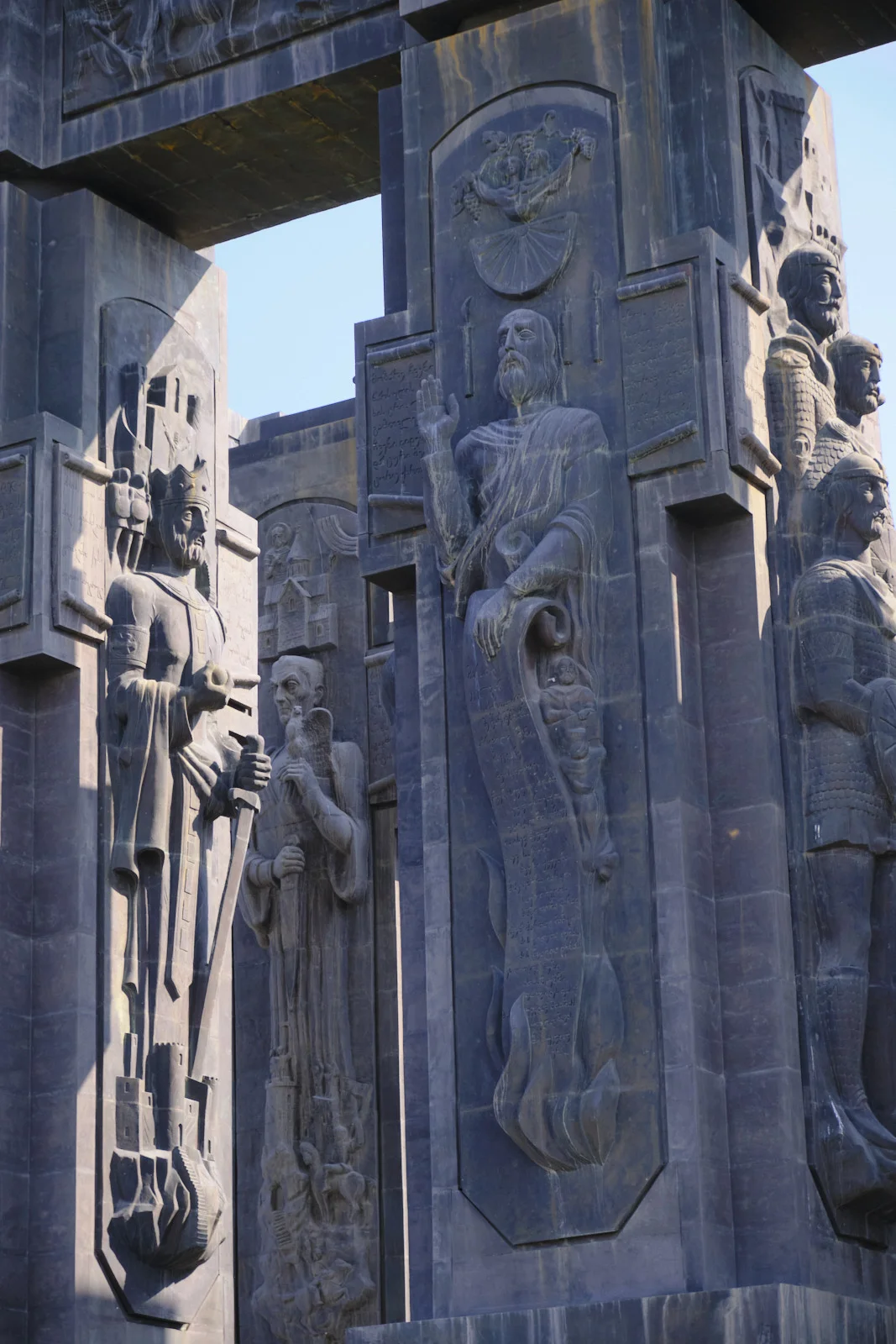 Close view of carved kings and a blessing figure on the dark stone of the Chronicle of Georgia.