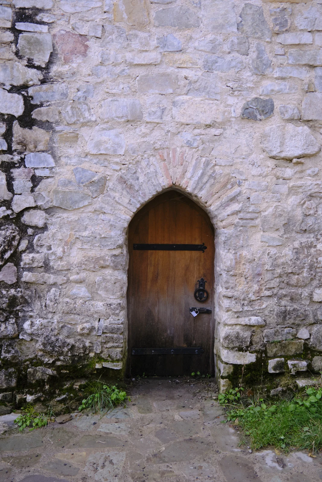 A plain wooden door set in a pointed stone arch of the fortress wall.