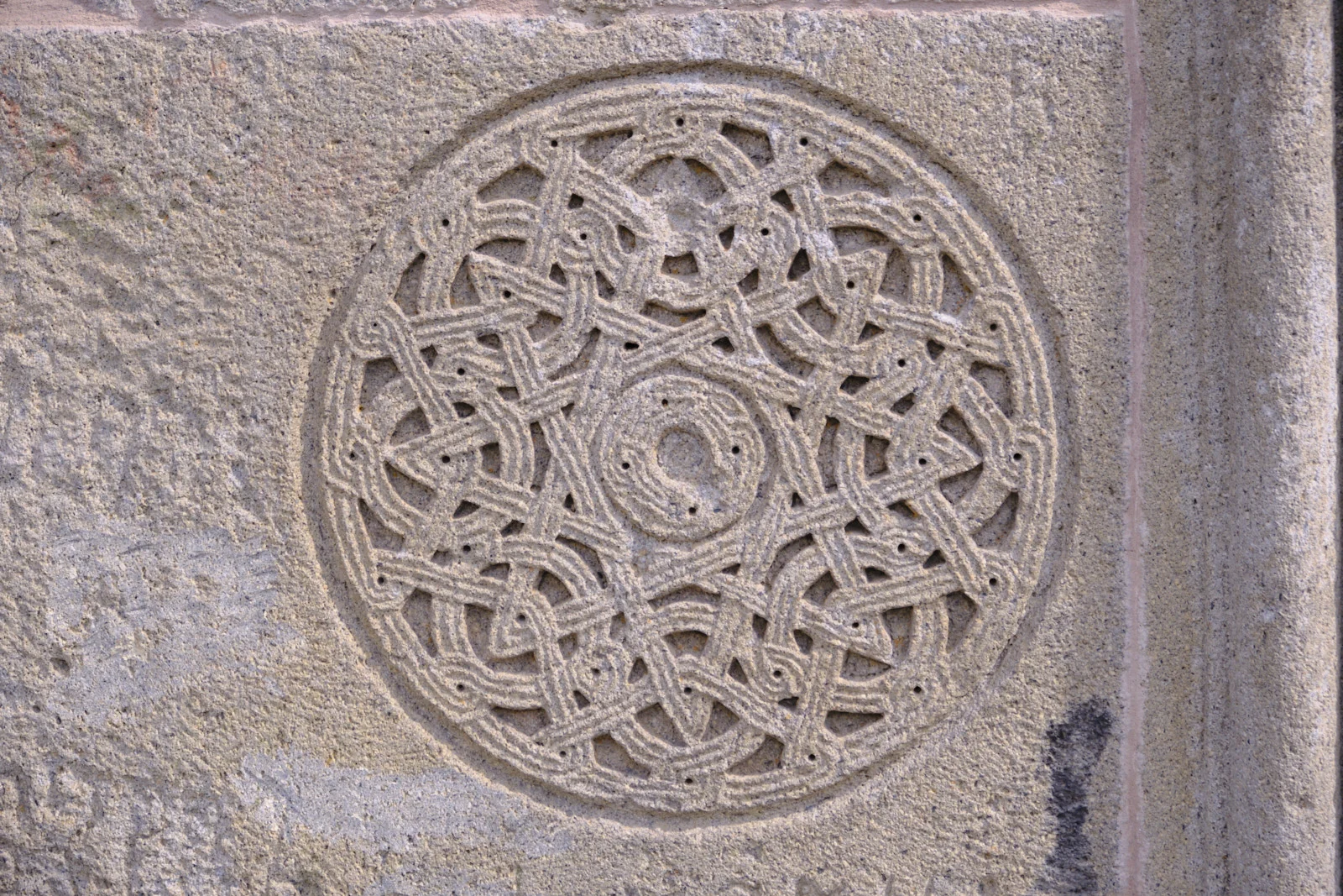 A circular carved knotwork medallion in a stone block.