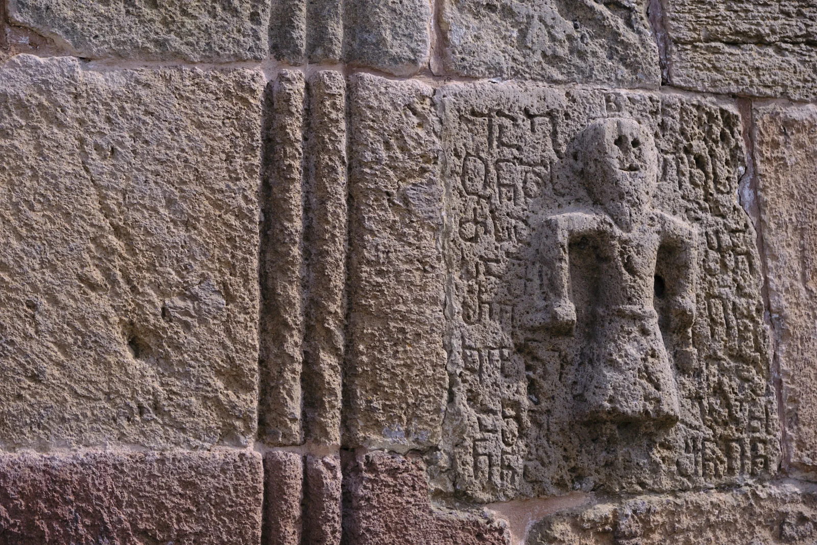 A small standing figure carved among lines of old Georgian letters.