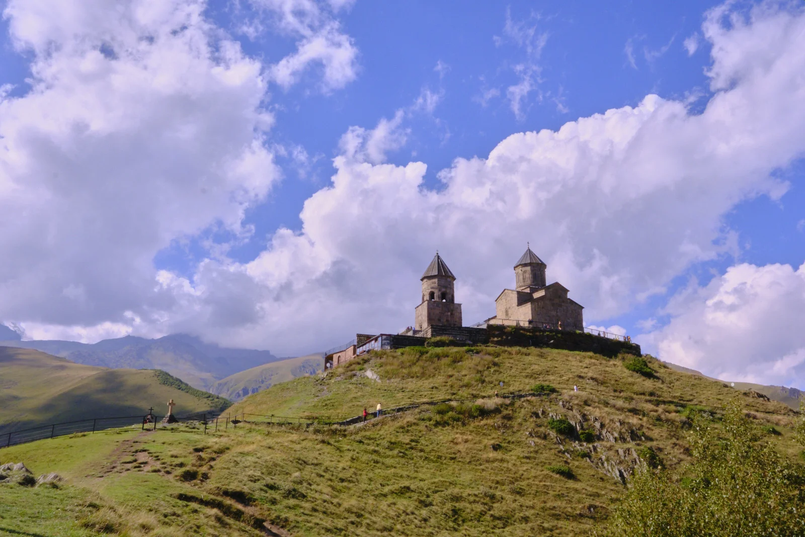 Gergeti Trinity on the skyline of its hill, under a bright pile of cloud.