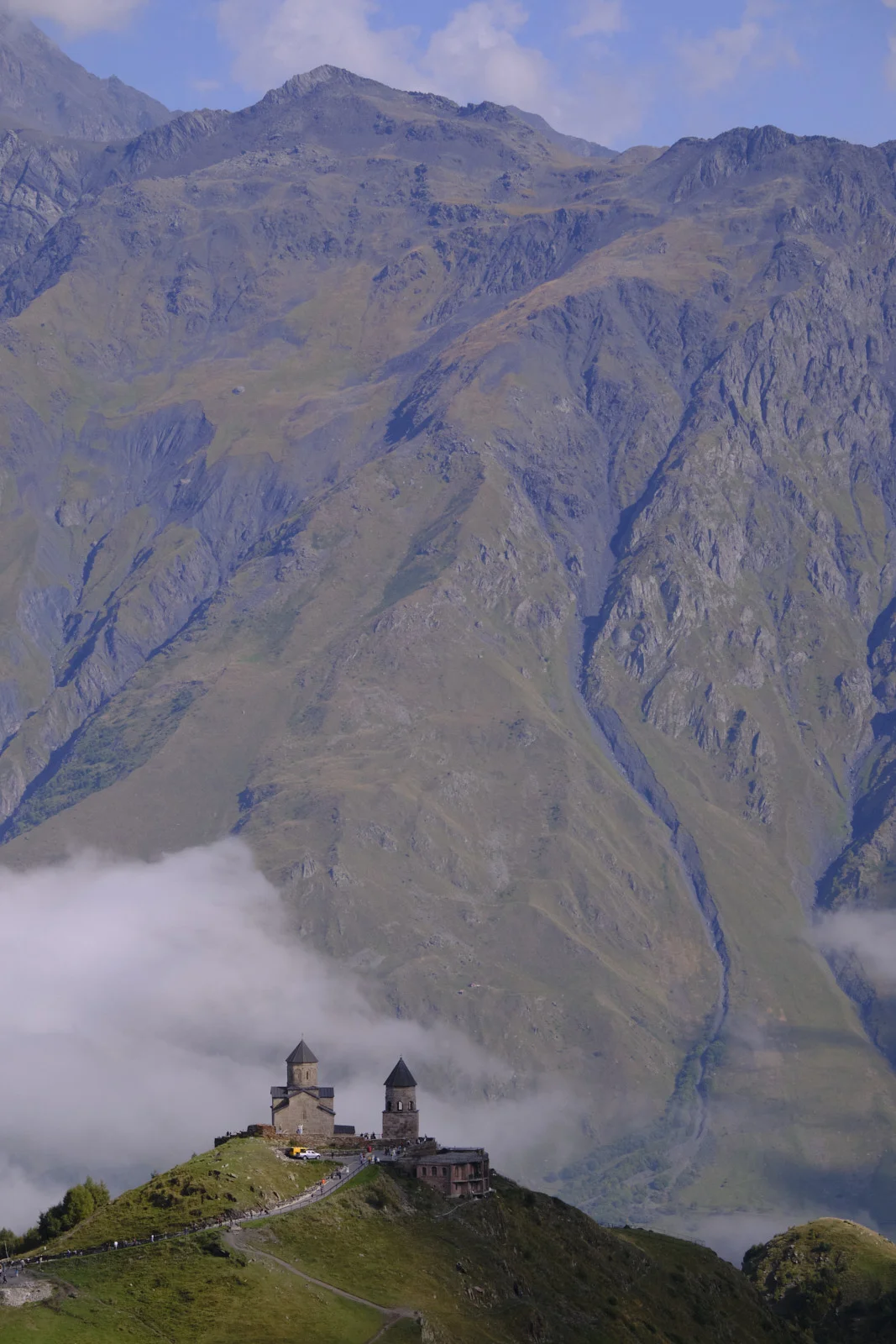 Gergeti Trinity on its ridge, cloud filling the valley and mountains behind.