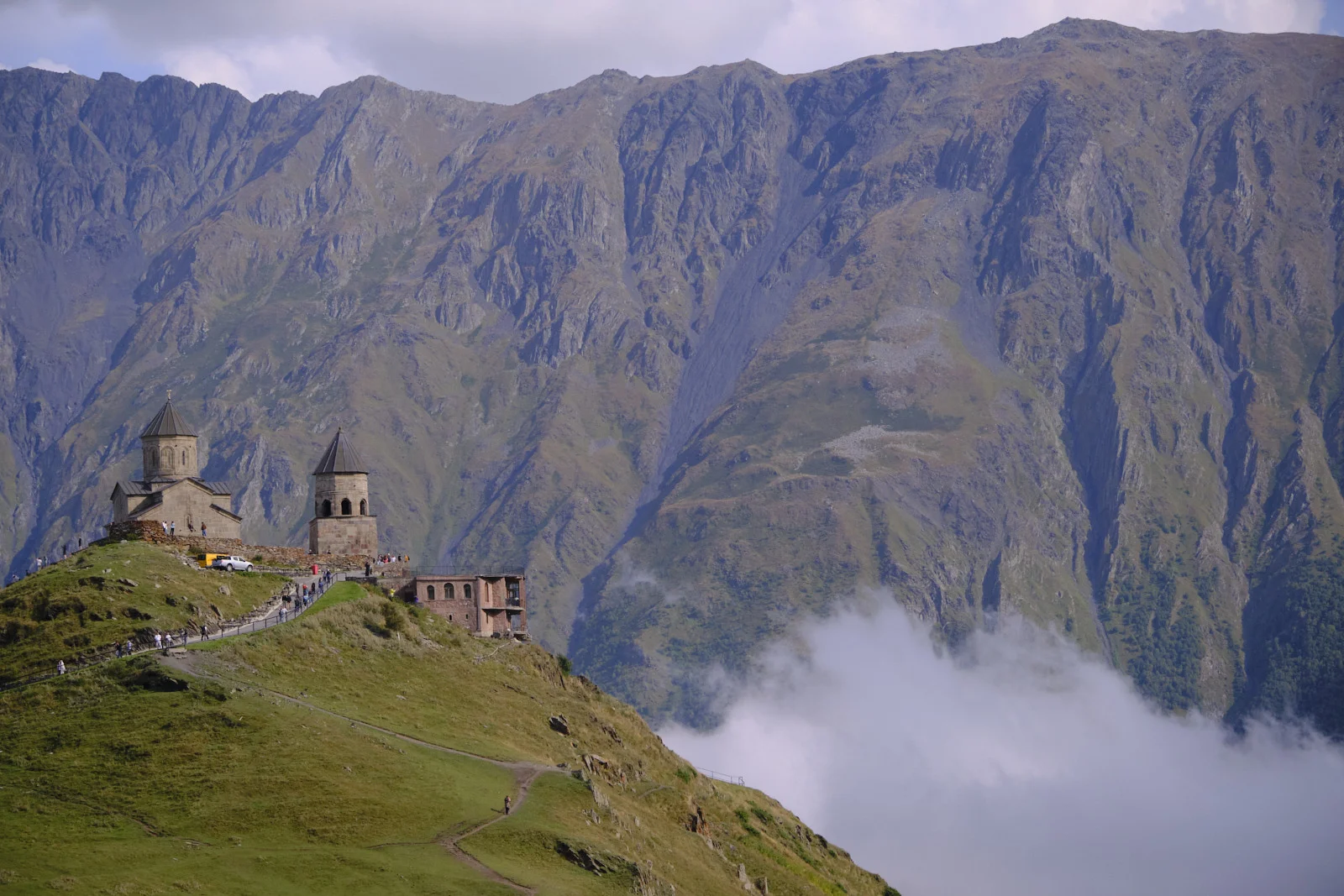 Gergeti Trinity on its ridge, with the steep wall of the mountain behind and cloud below.