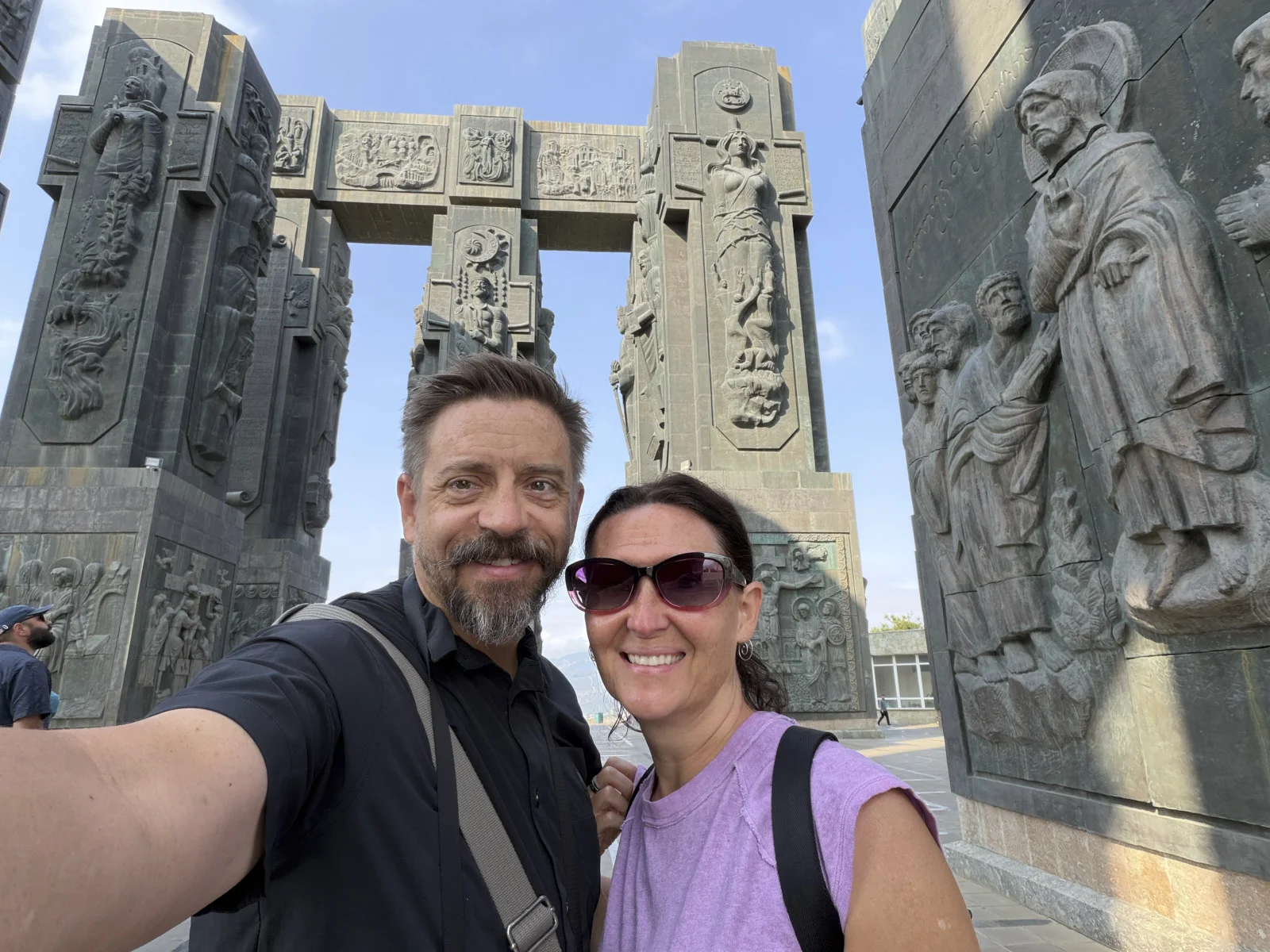 A couple taking a selfie beneath the carved pillars of the Chronicle of Georgia.