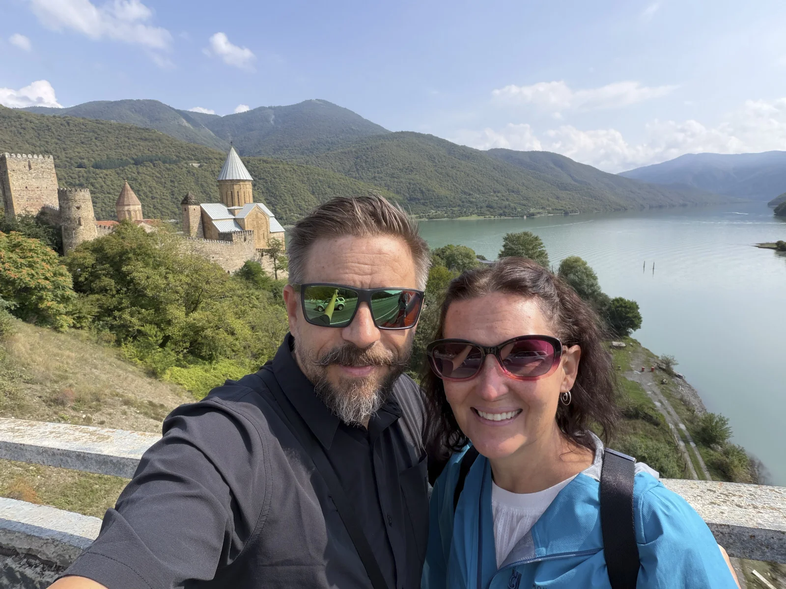 A couple taking a selfie above Ananuri, the church towers and the reservoir behind them.