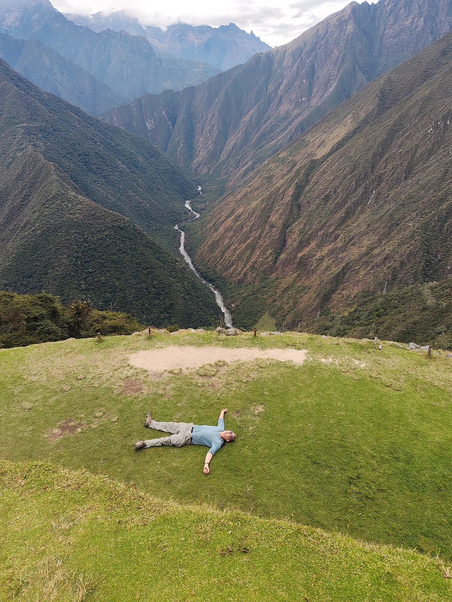 Steve lying on a grassy terrace above the deep Urubamba River valley