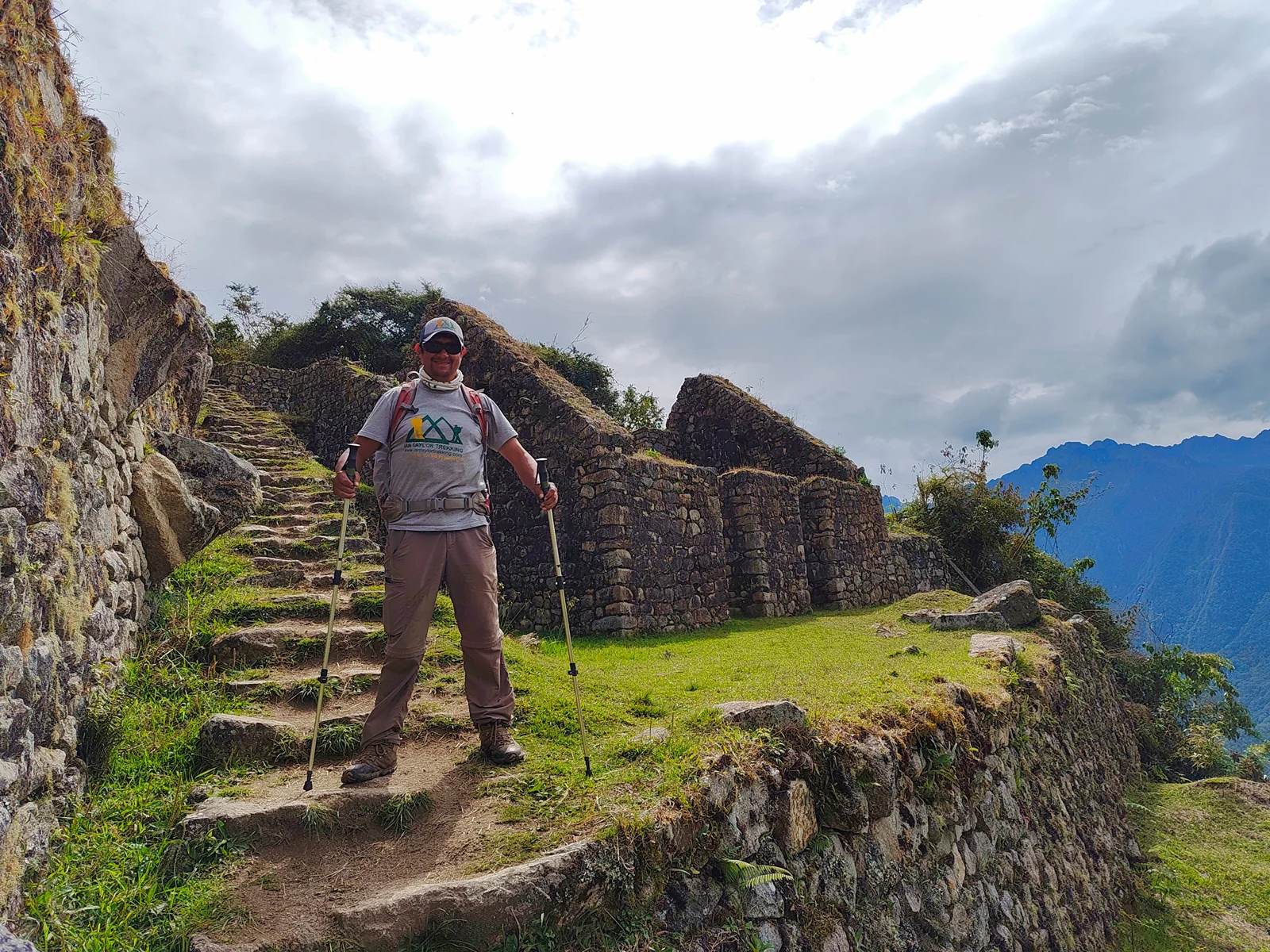 Percy standing with trekking poles on stone steps at Wiñay Wayna