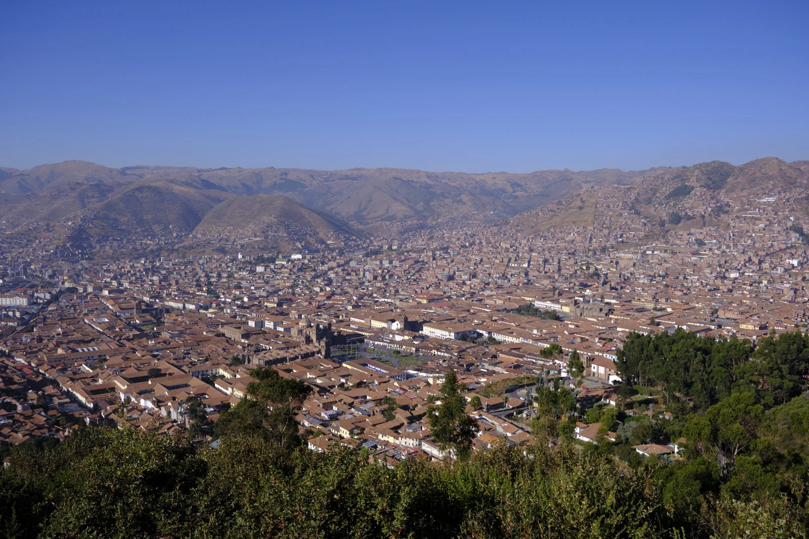 Cusco from the Cristo Blanco hillside, looking over the Plaza de Armas, the cathedral, and terracotta roofs to the surrounding mountains
