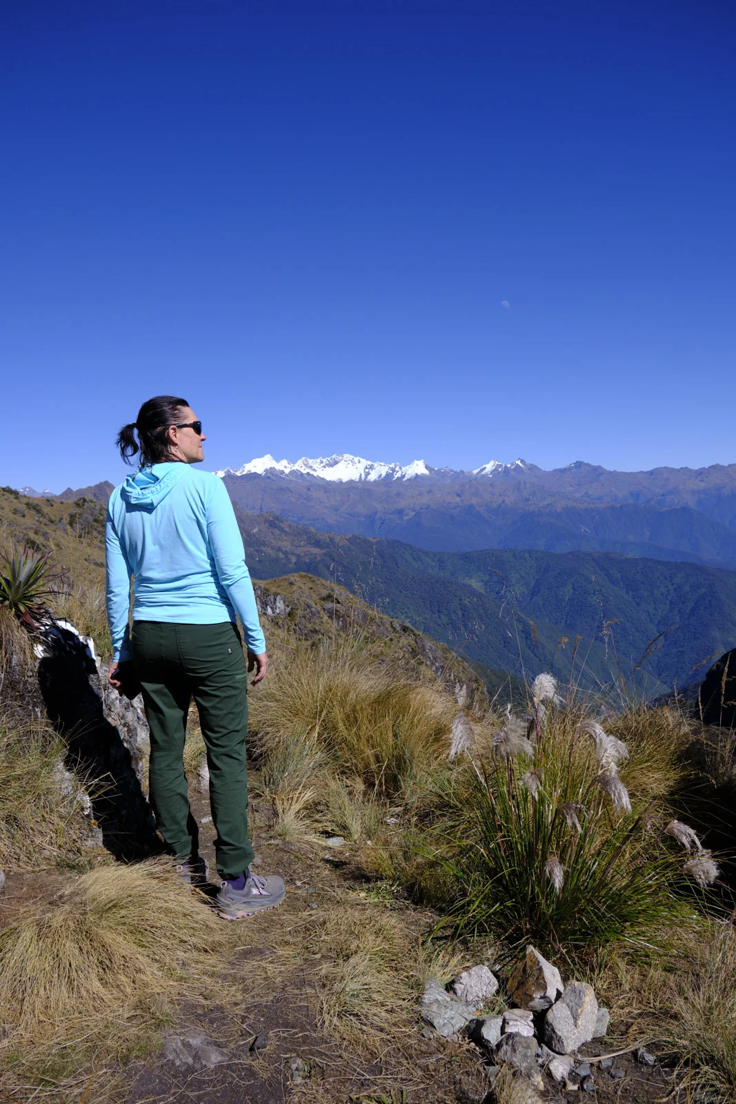 Ridge near Sayacmarca looking toward snow-capped Salkantay and the Vilcabamba range, with puna grass and a faint moon