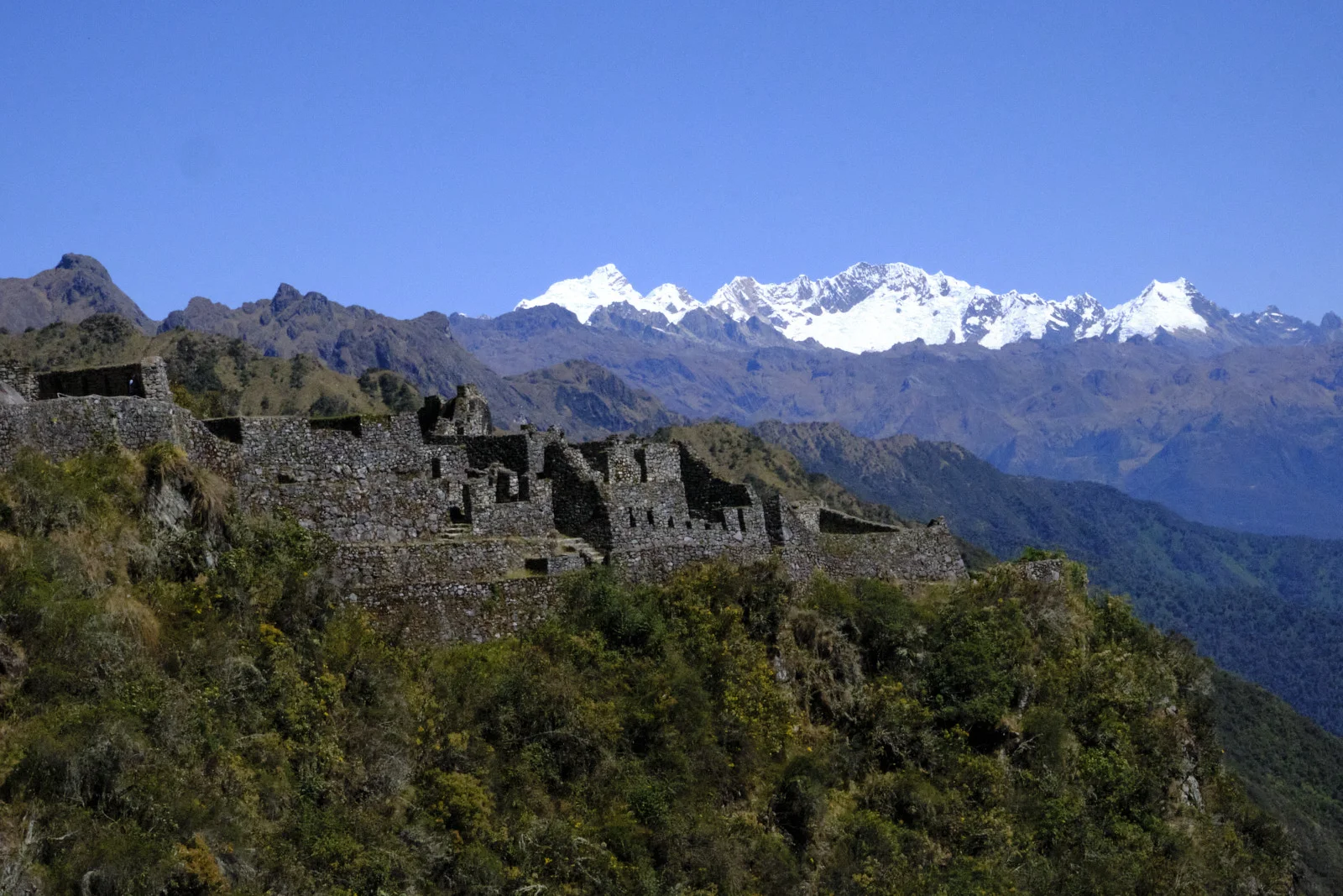 Sayacmarca’s dry-stone rooms and terraces on the cliff, Salkantay’s snow peaks on the horizon