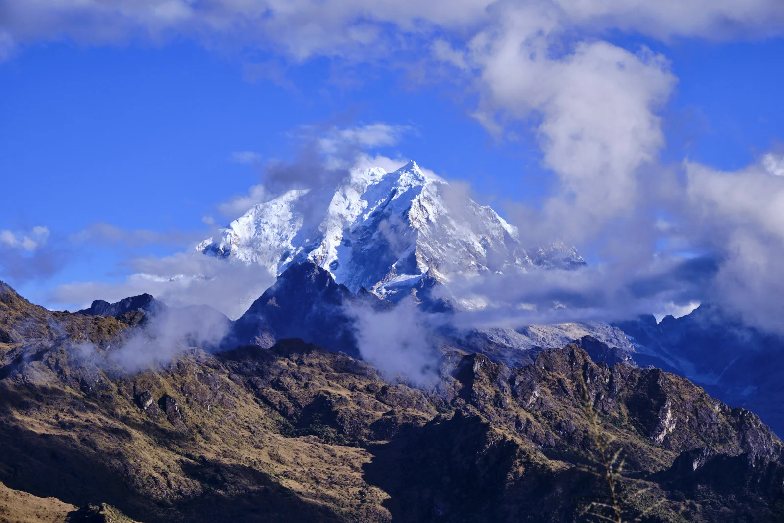Salkantay partly in cloud, seen from Phuyupatamarca across dark rocky ridges