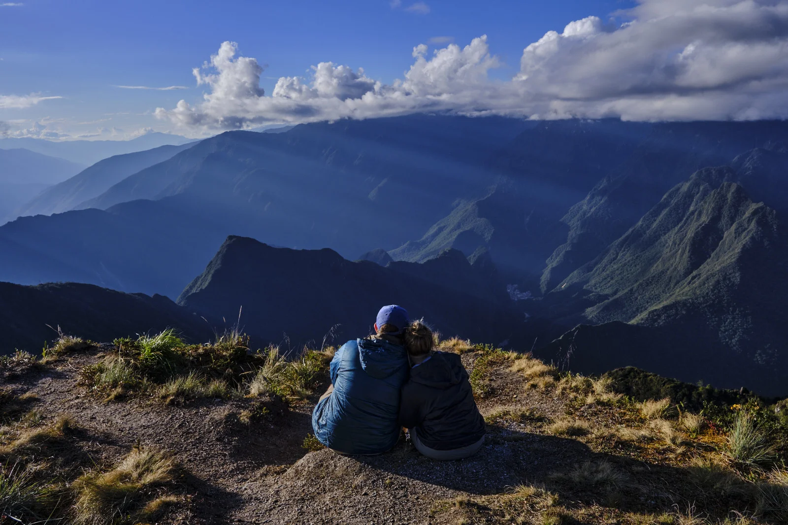 Viewpoint above Phuyupatamarca camp, layered ridges and sun rays toward the cloud-forest valleys