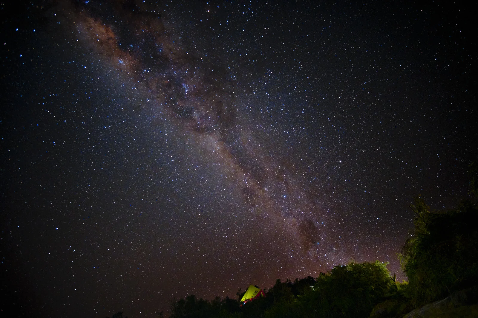 Milky Way over Phuyupatamarca camp, a lit tent among the trees