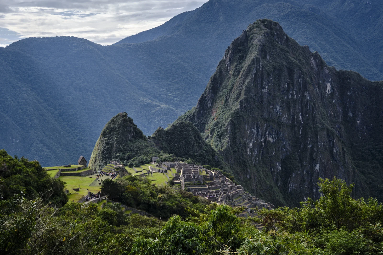Machu Picchu from the Intipunku (Sun Gate) approach: the citadel and thatched Guardhouse, Huayna Picchu behind, Putucusi to the left