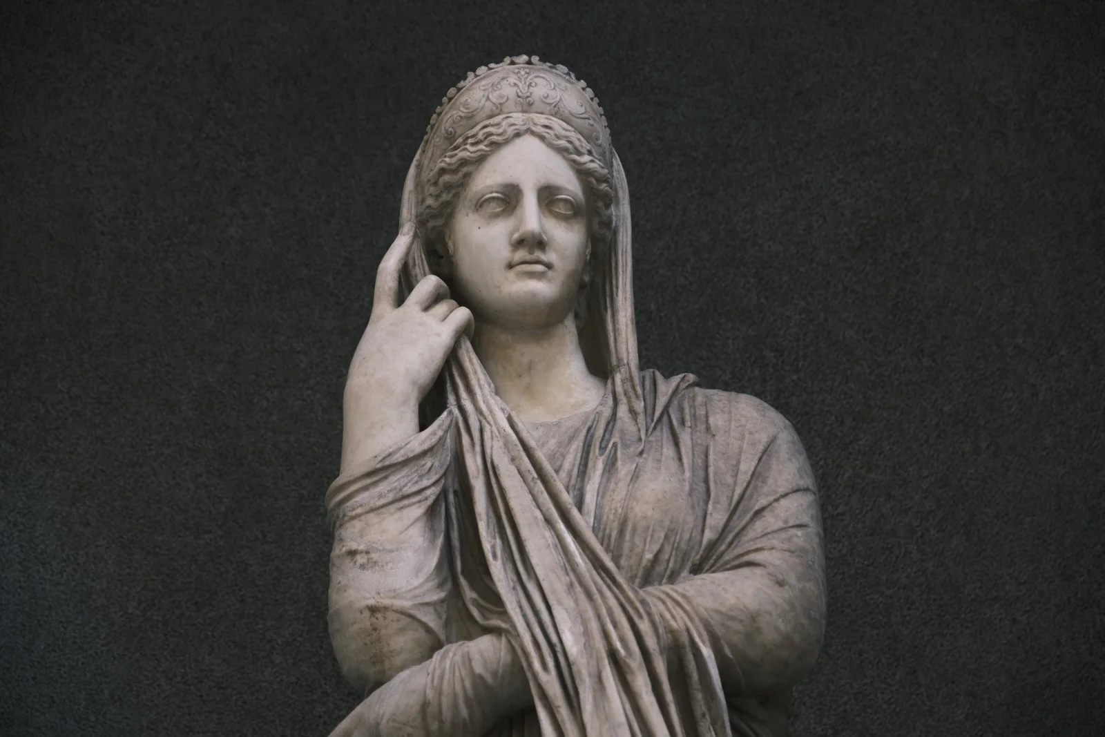 Marble statue of a veiled woman touching her headdress