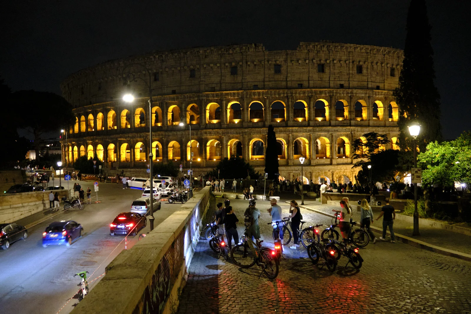 Colosseum at night with bicycle riders in the foreground