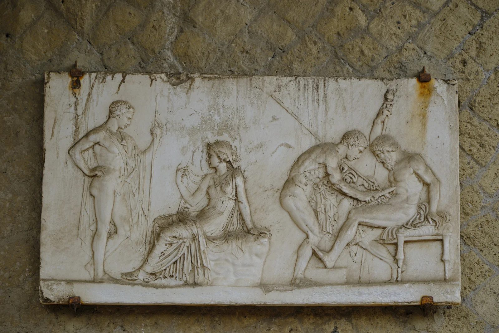 Marble relief of seated woman and three men on a stone wall