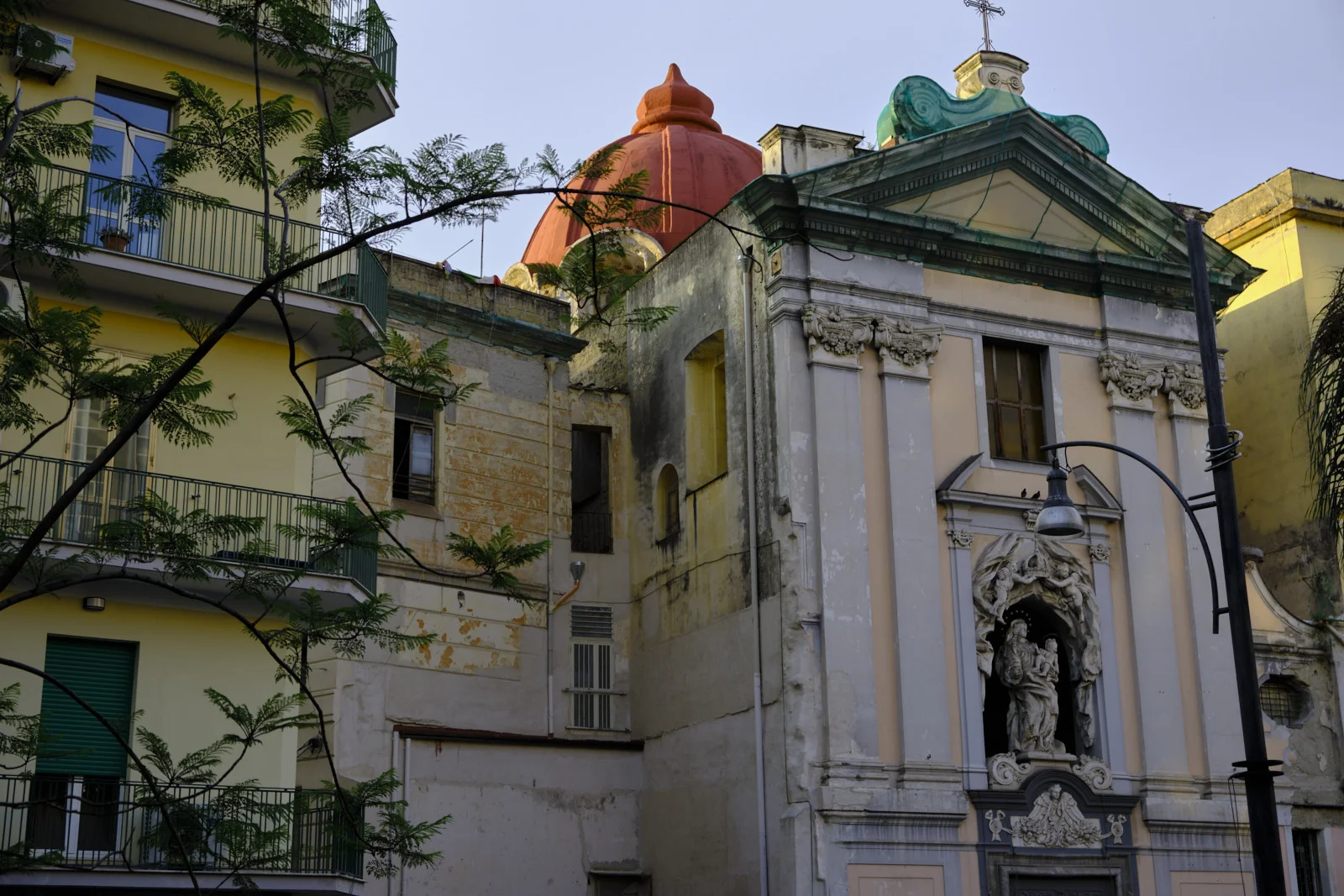 Neapolitan church with a red dome beside yellow apartments