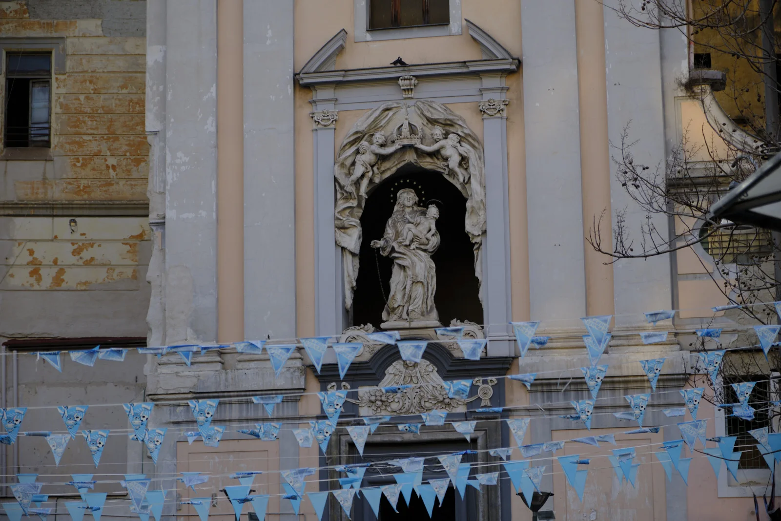 Church niche with Madonna and Child and blue pennants in Naples