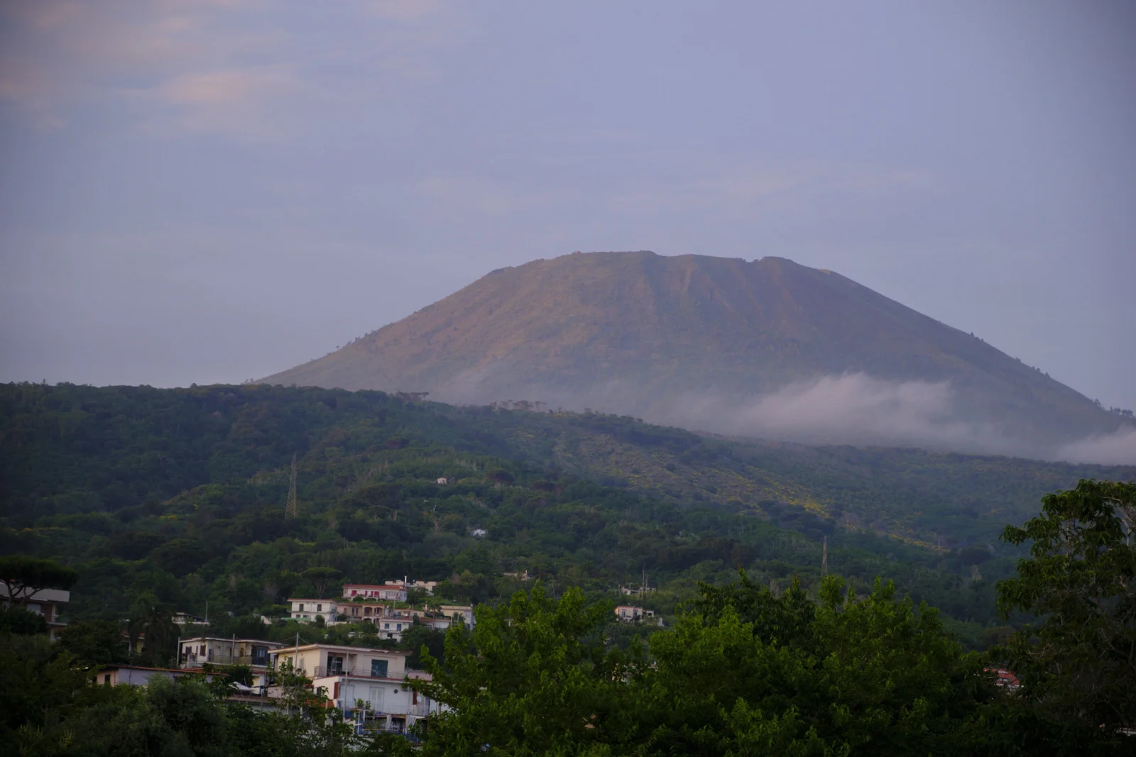 The cone of Mount Vesuvius above a wooded slope and houses