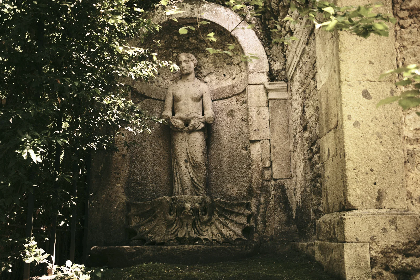 Stone statue of a woman in a garden niche at Bomarzo