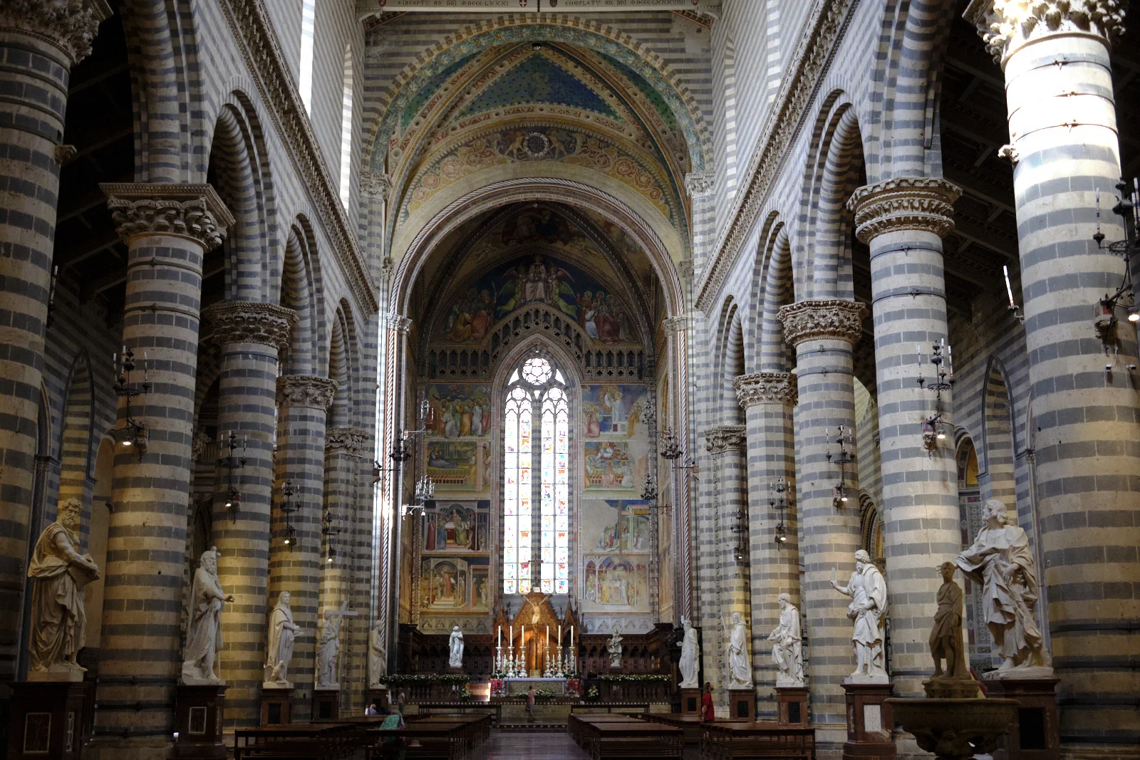 Interior of Orvieto Cathedral with striped columns and a frescoed apse