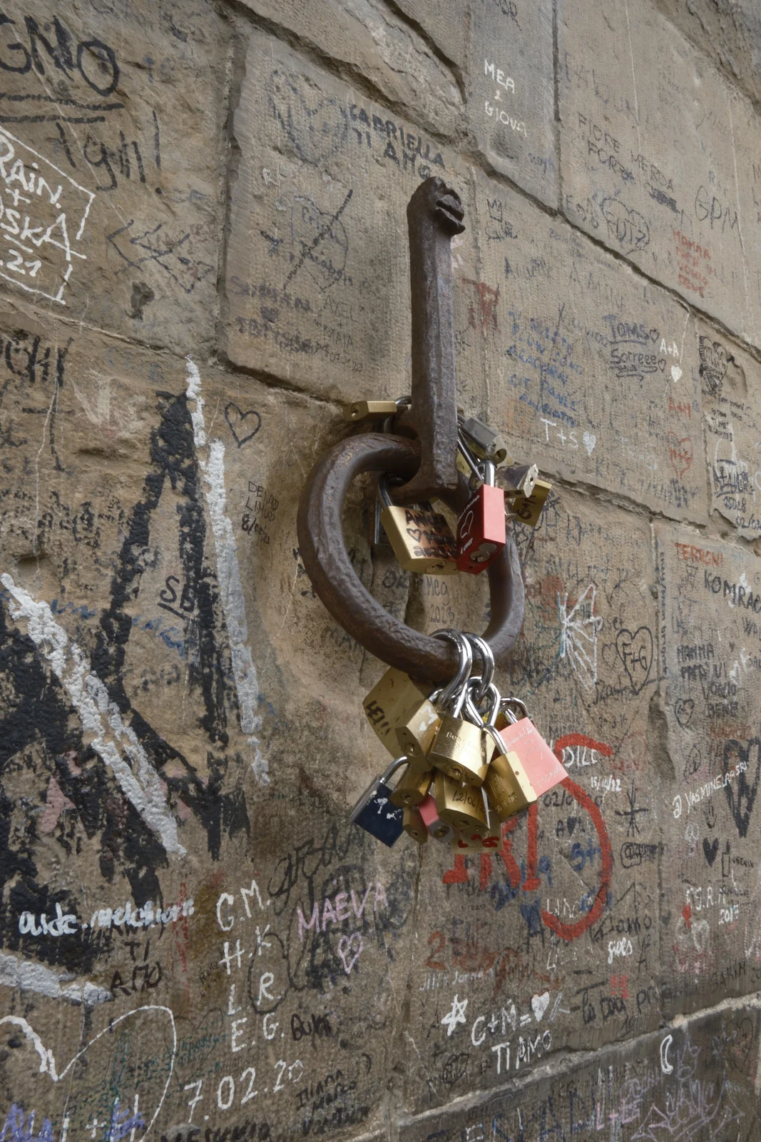 Padlocks hanging from a rusty ring on a carved stone wall