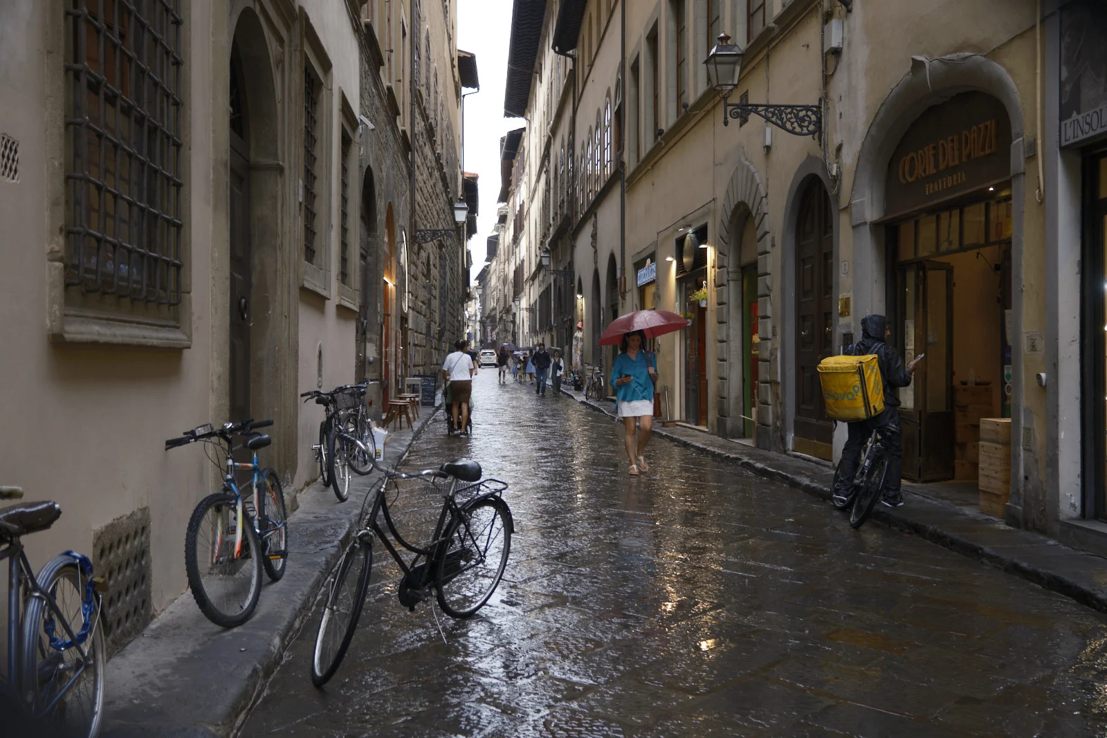 Rain-slick Florence street with bicycles and a trattoria