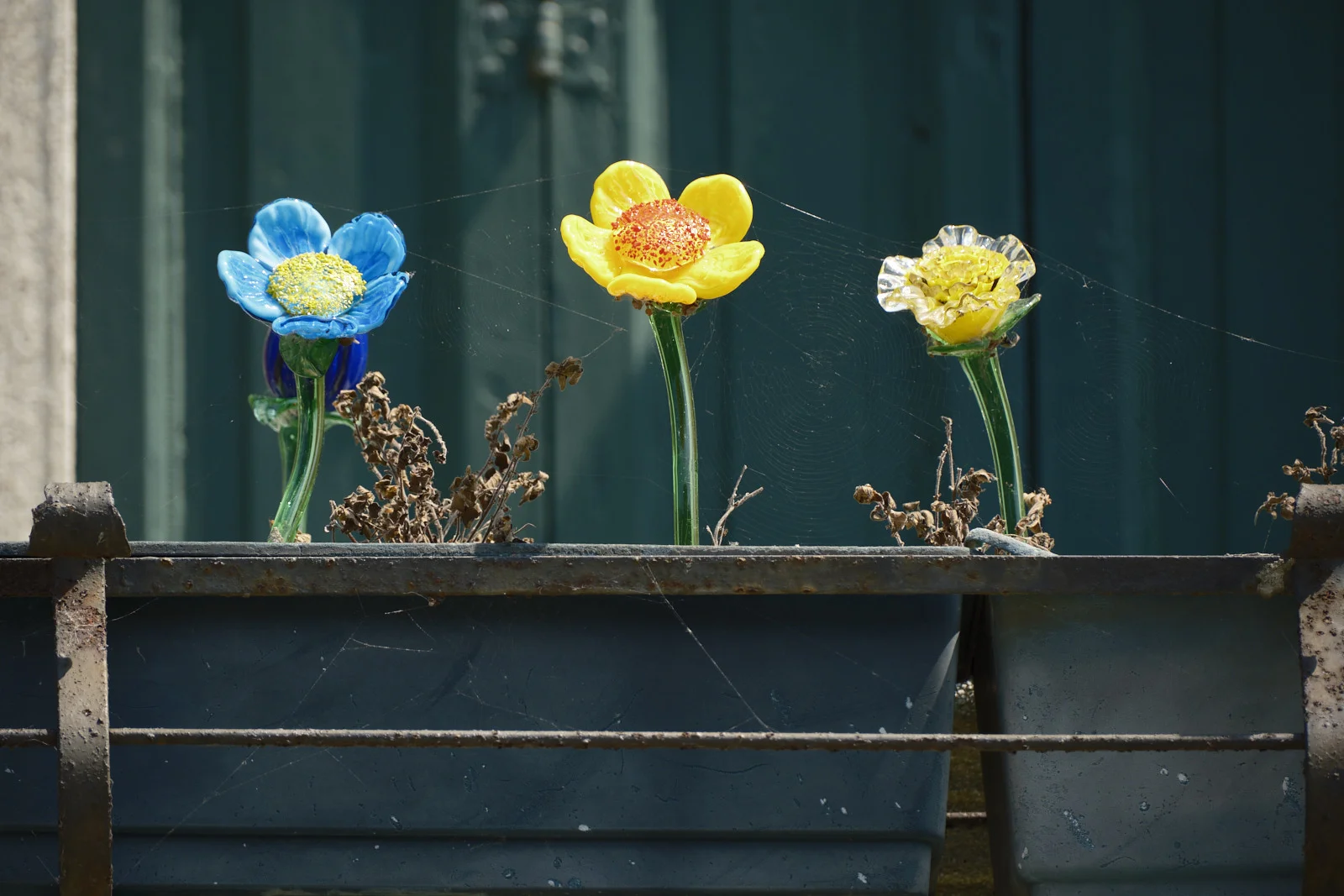 Blue and yellow glass flowers in a rusty planter