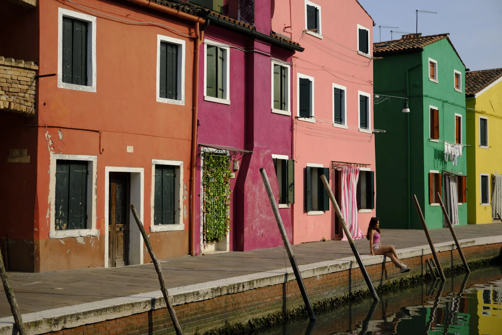 Colorful Burano facades and a person sitting by the canal