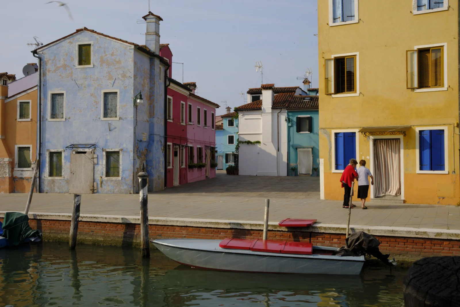 Peeling blue house and a yellow facade on a Burano quay