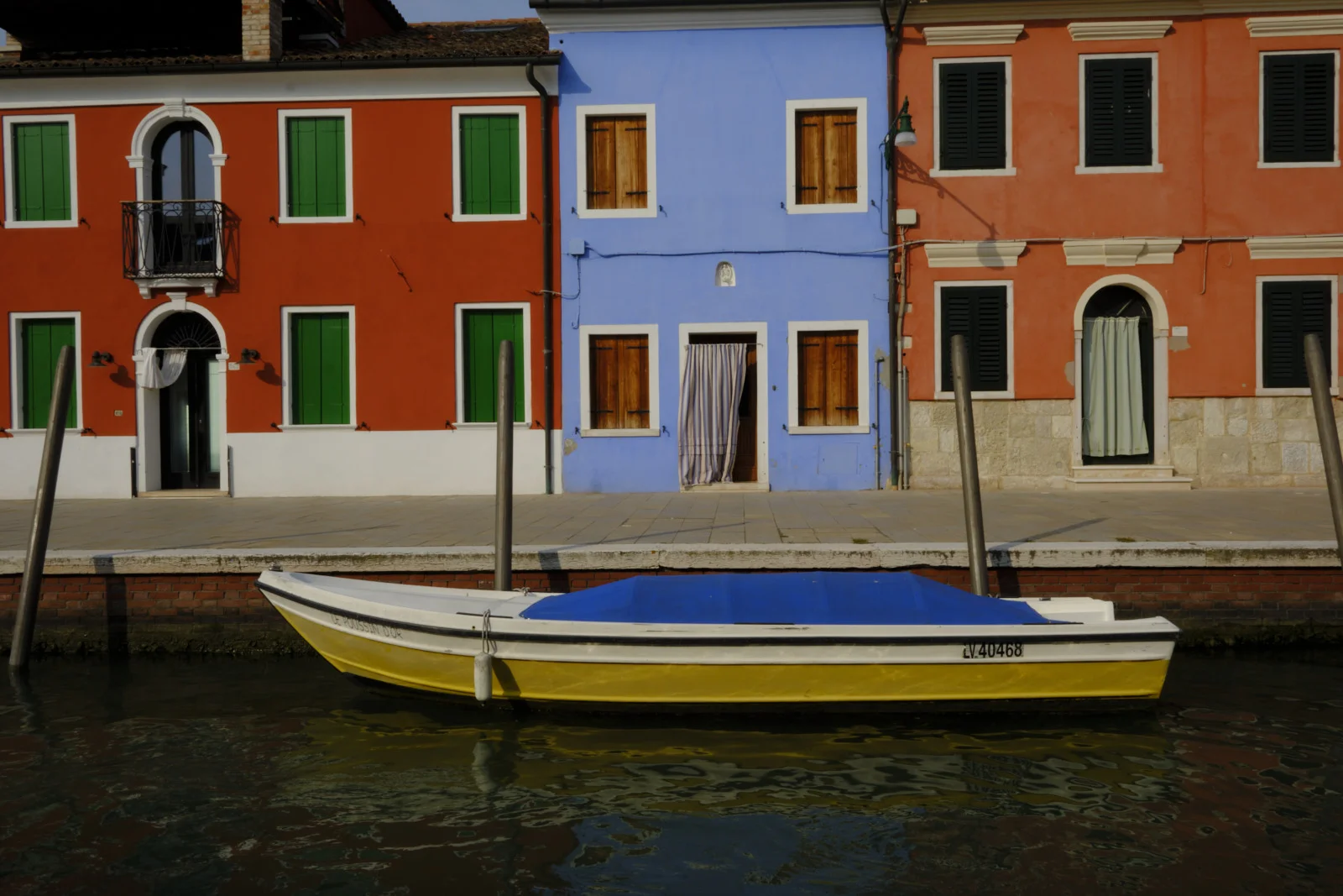 Yellow boat moored in front of painted Burano houses