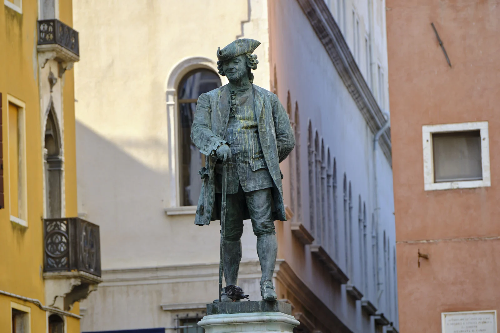 Bronze statue of a smiling 18th-century man with a cane