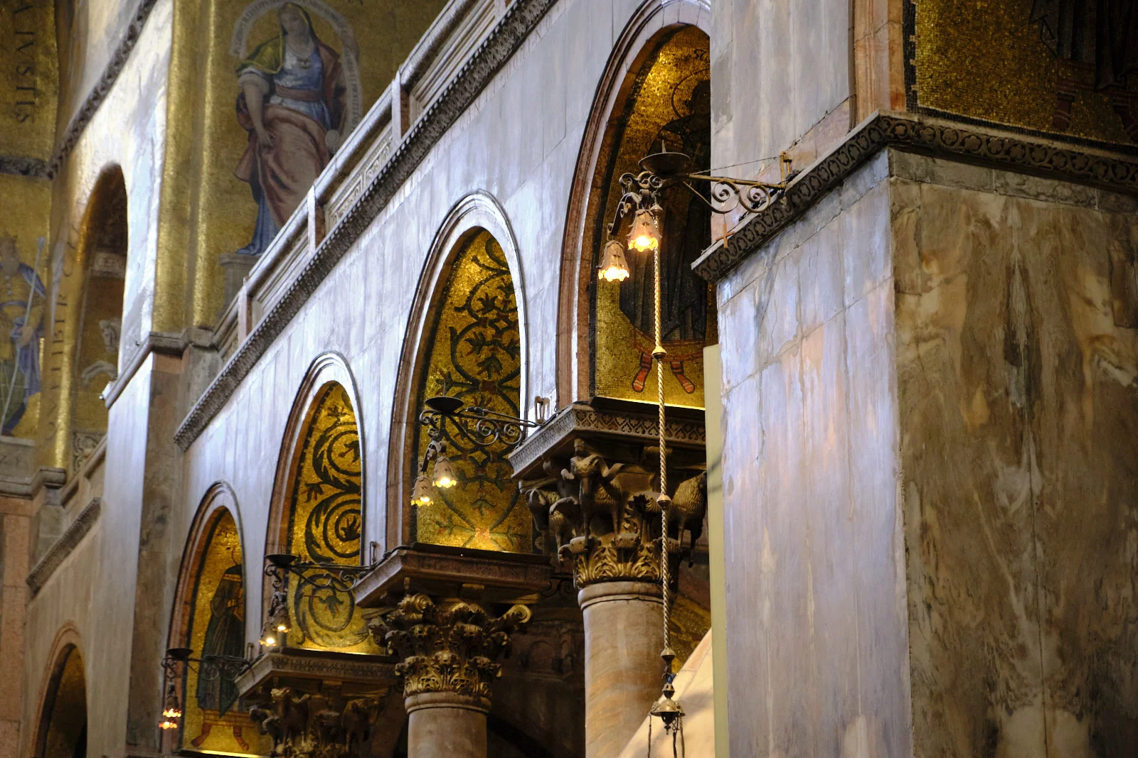 Gold mosaic lunettes and marble columns in the gallery of St. Mark’s Basilica