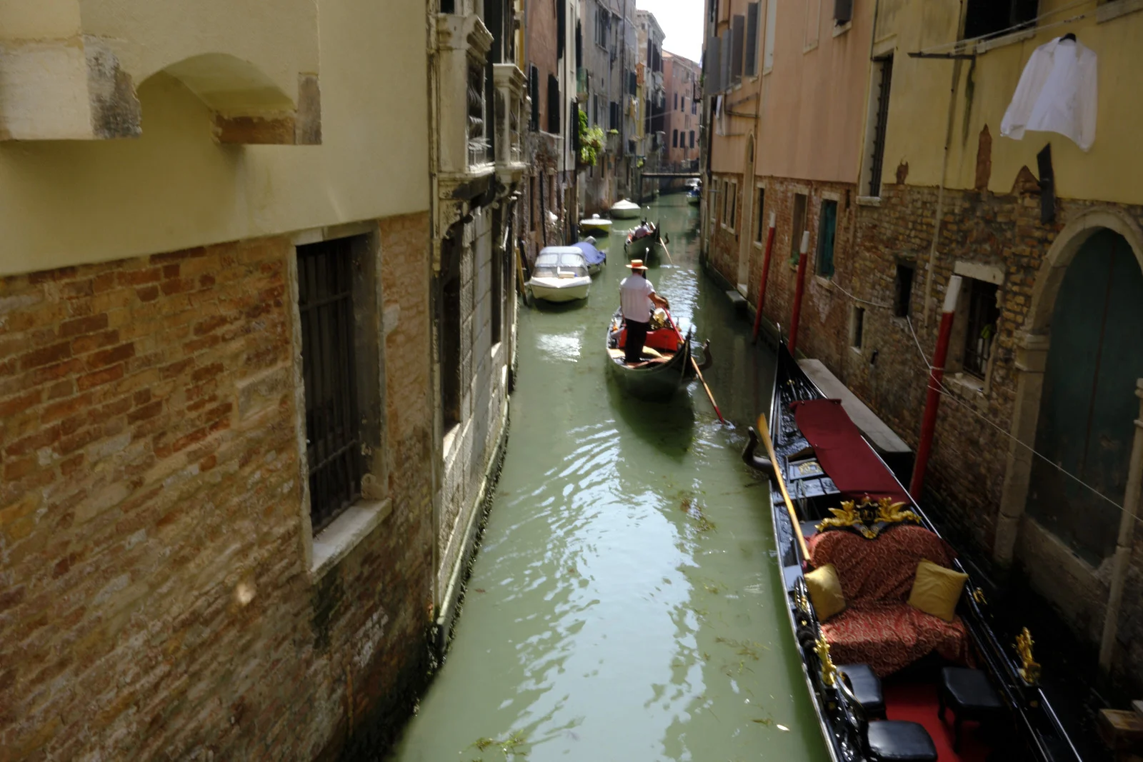 Gondola on a narrow Venice canal seen from a bridge