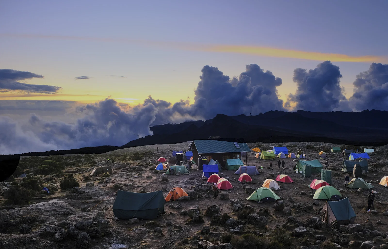 Shira Camp at dusk with colorful tents and a green-roofed hut