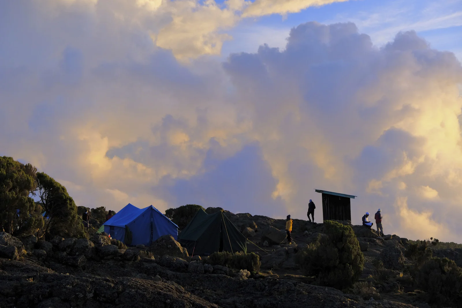 Blue and green tents on lava rock under evening cloud