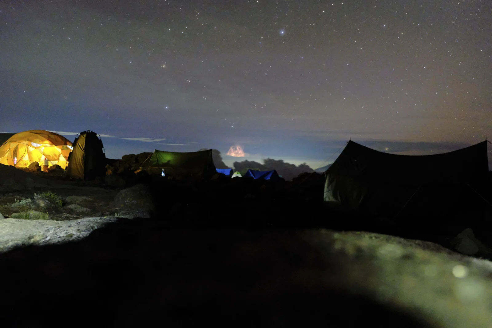 Starry sky over glowing tents at high camp