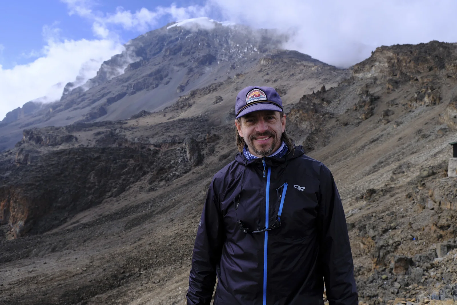 Climber in a cap standing below the Kibo summit cone