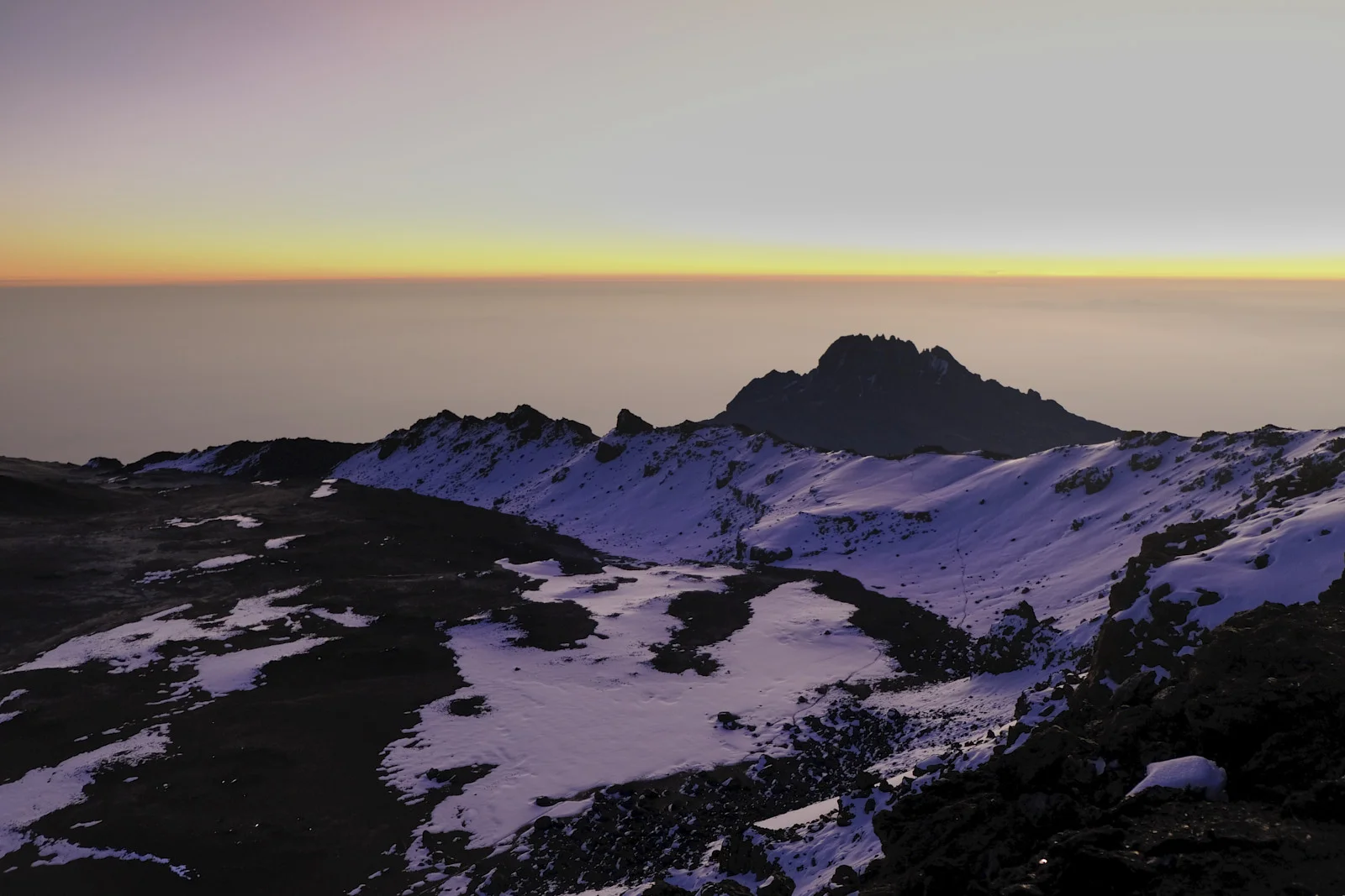 Mawenzi silhouetted beyond snow in Kilimanjaro’s crater