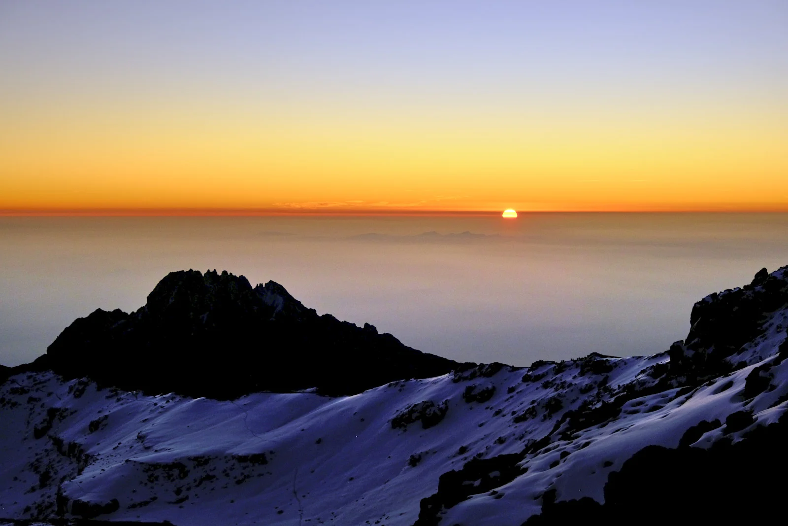 Sun rising on the horizon beyond Mawenzi’s silhouette