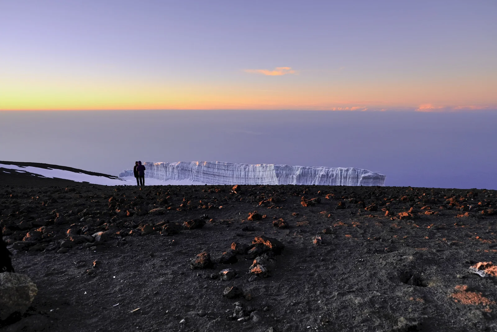 Two people standing before the Furtwängler Glacier at dawn