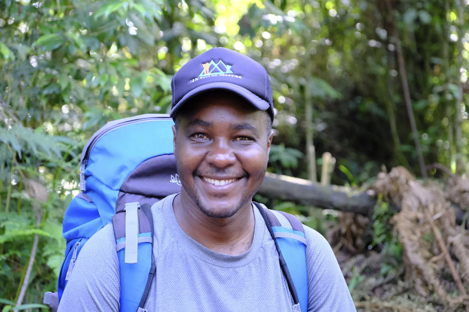 Guide in an Ian Taylor Trekking cap smiling on the forest trail