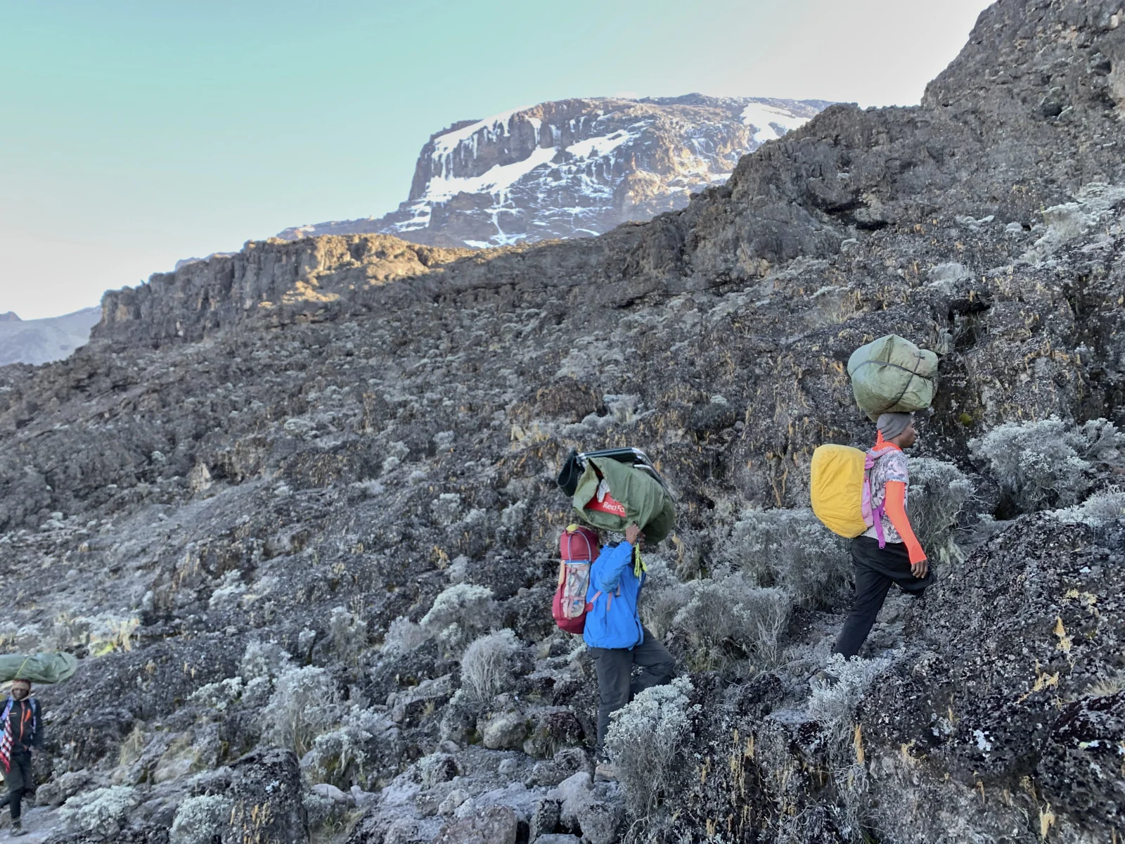 Porters scrambling the Barranco Wall with Kibo’s ice above