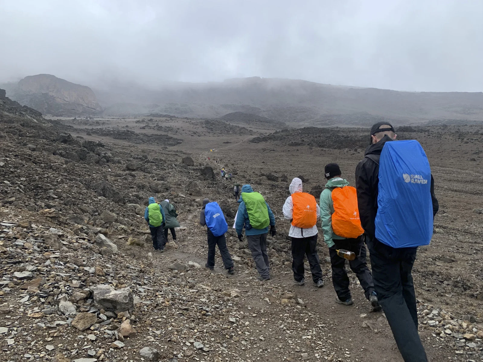 Hikers descending a rocky trail into a grey alpine valley