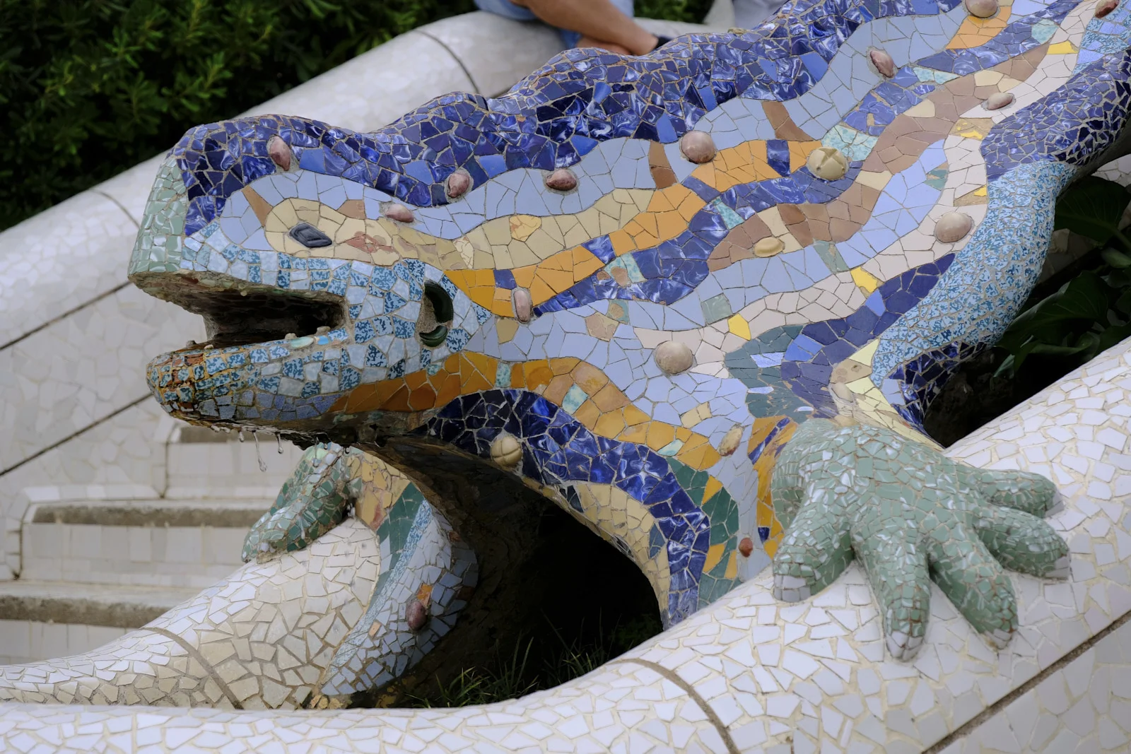 The mosaic dragon El Drac on the entrance stairway at Park Güell in Barcelona, with water at its mouth.