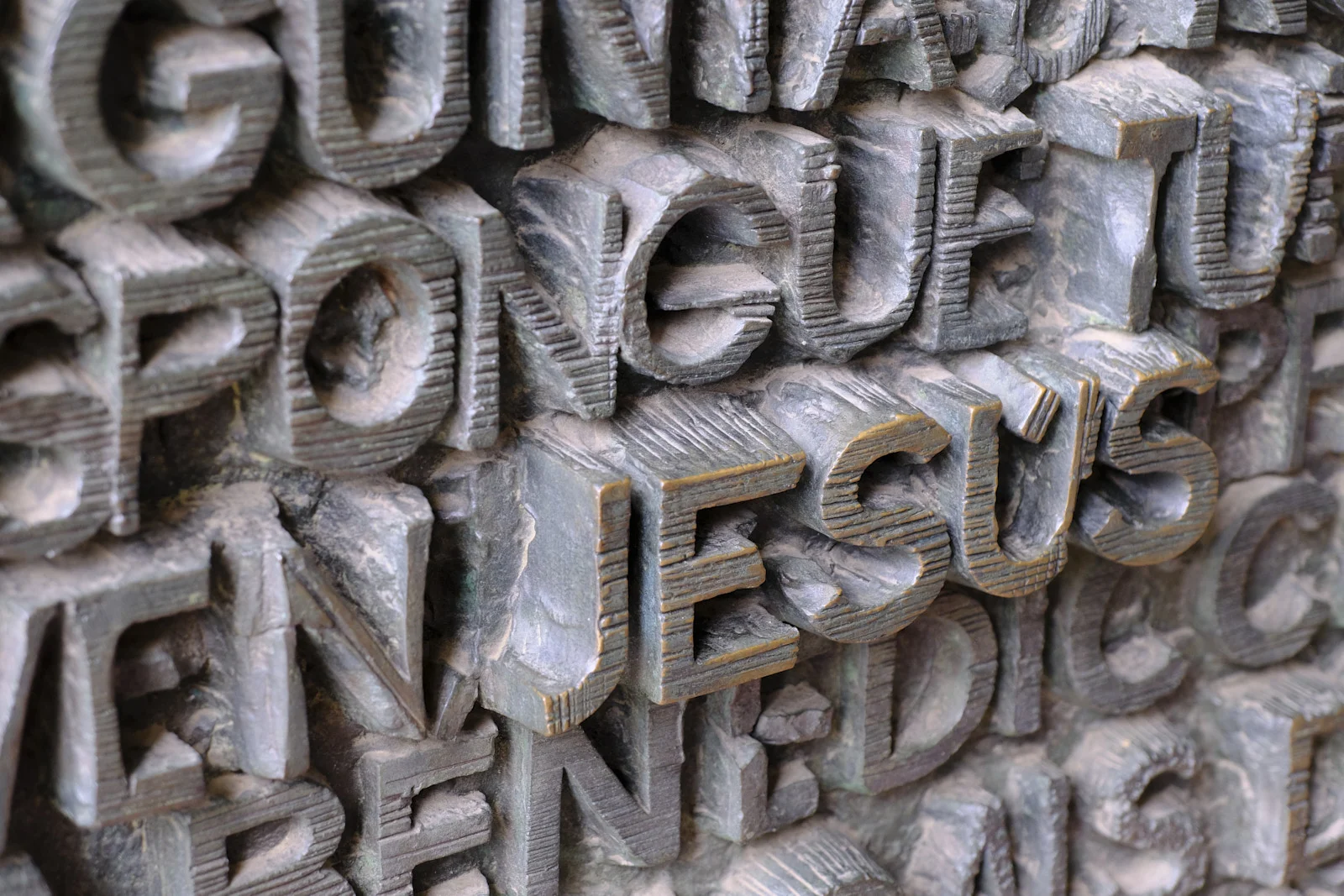 Bronze door lettering on the Passion facade of the Sagrada Família in Barcelona, with the name Jesus visible.